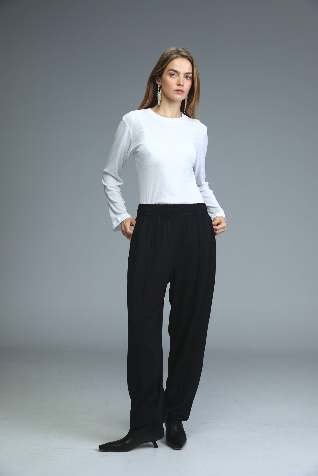 White long-sleeved top with round neckline and slightly flared cuffs shown from the front for best black joggers product