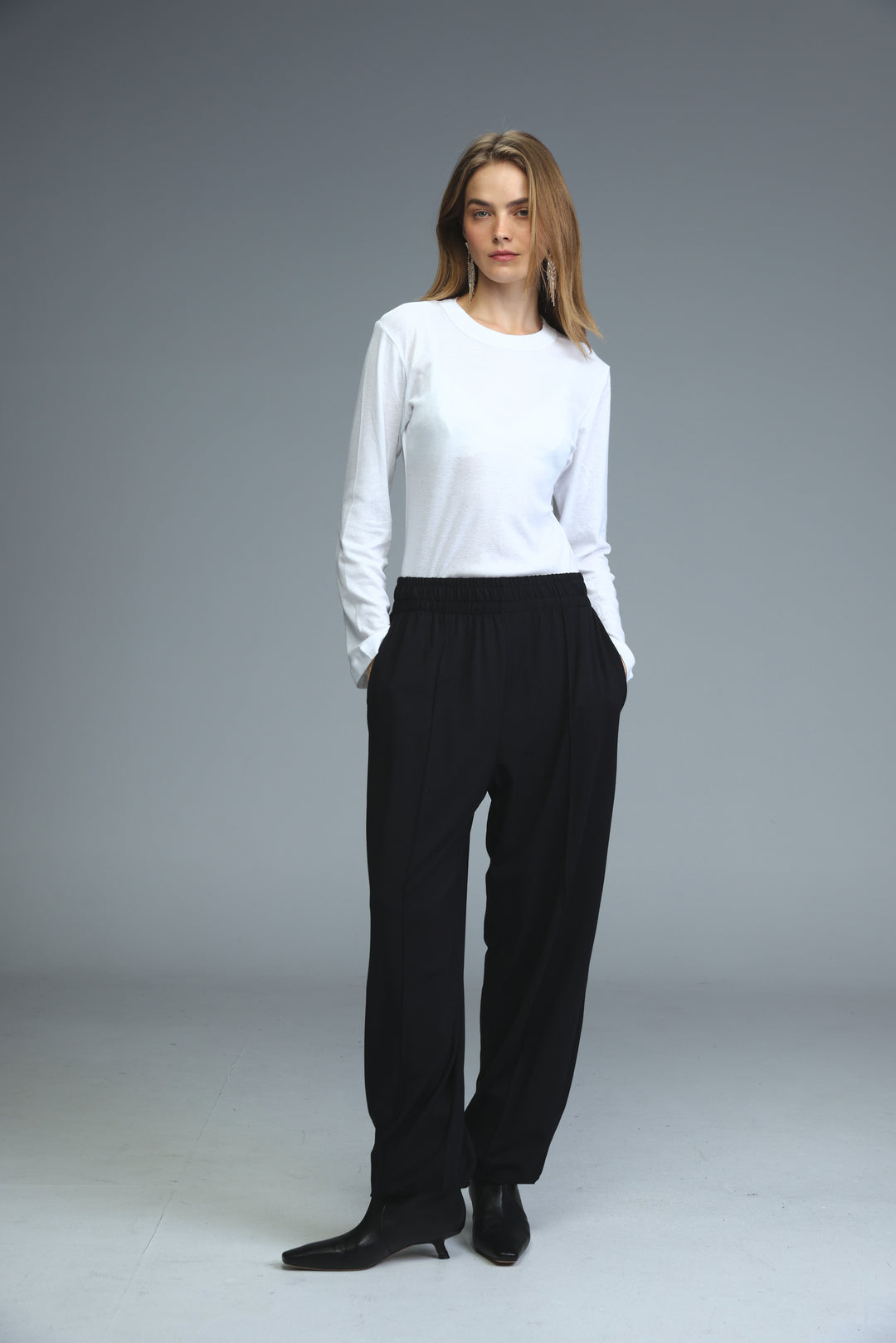 Black high-waisted joggers shown front view paired with a minimalist white long-sleeved top with round neckline