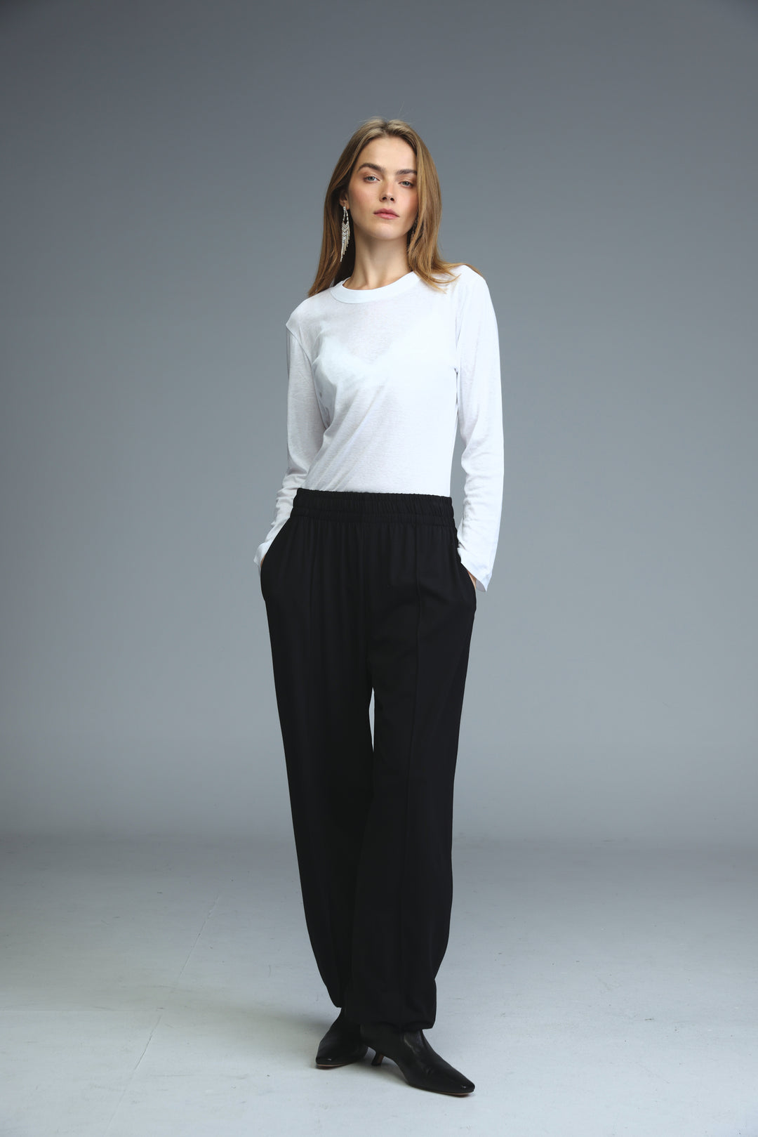 White minimalist long-sleeved top with round neckline and subtle side seam detailing shown from the front