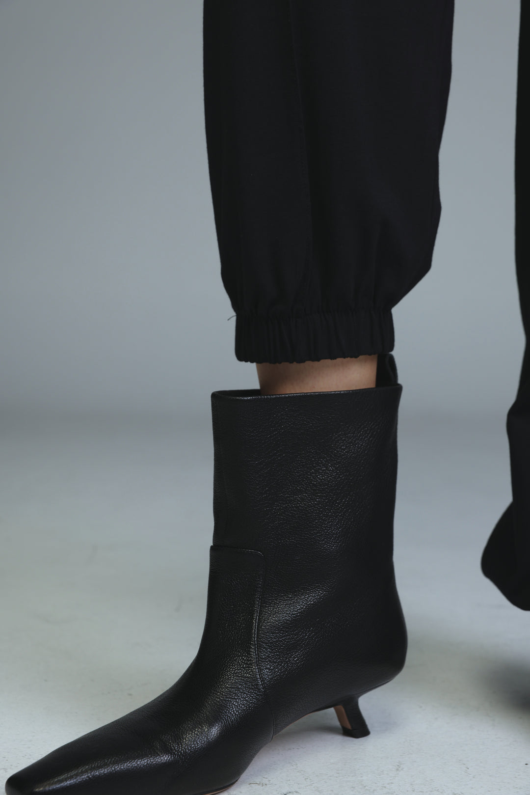 Black leather ankle boot with pointed toe and low kitten heel shown from side view for best black joggers