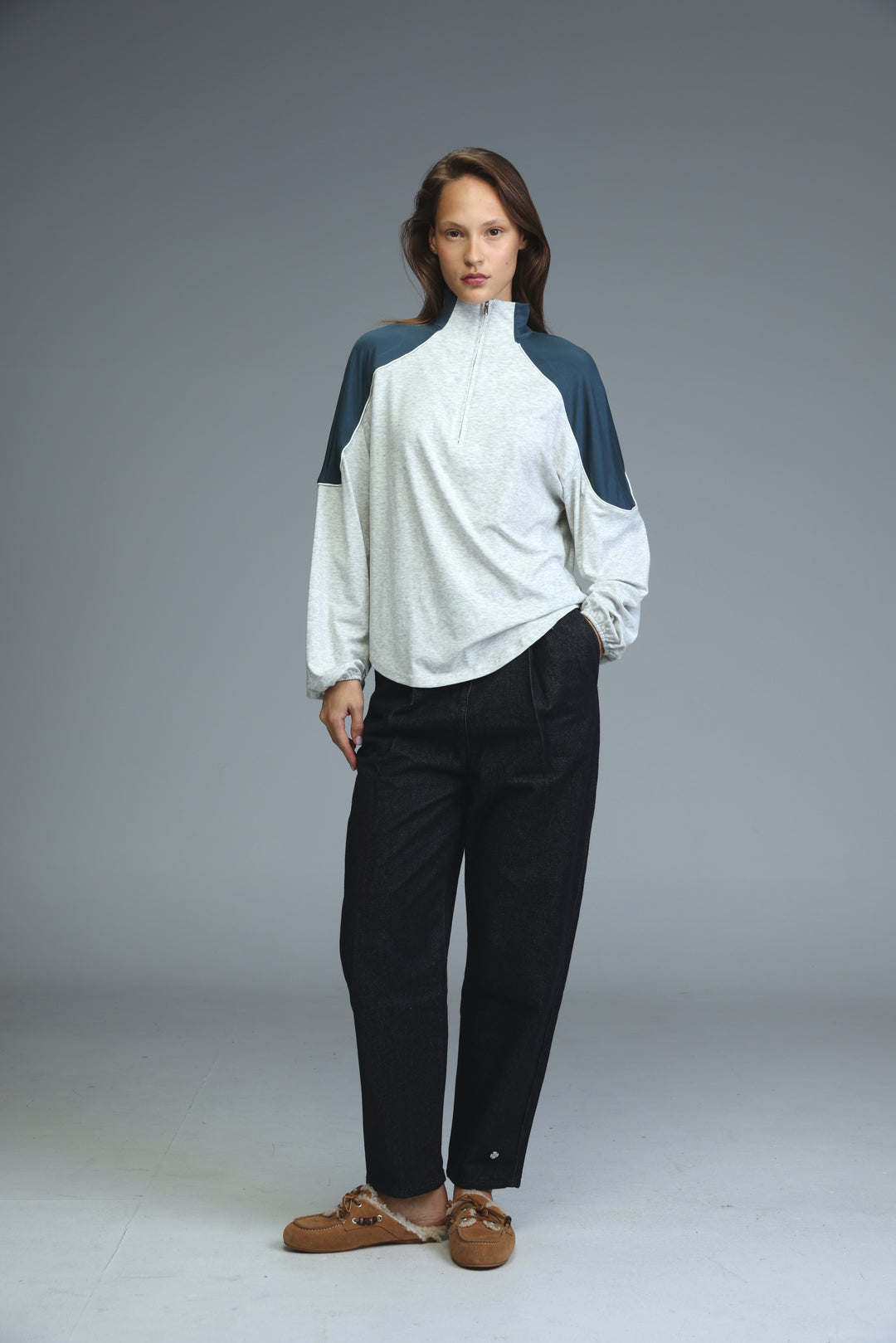 A white and navy blue zip-up track jacket with contrasting panels paired with black trousers shown from the front