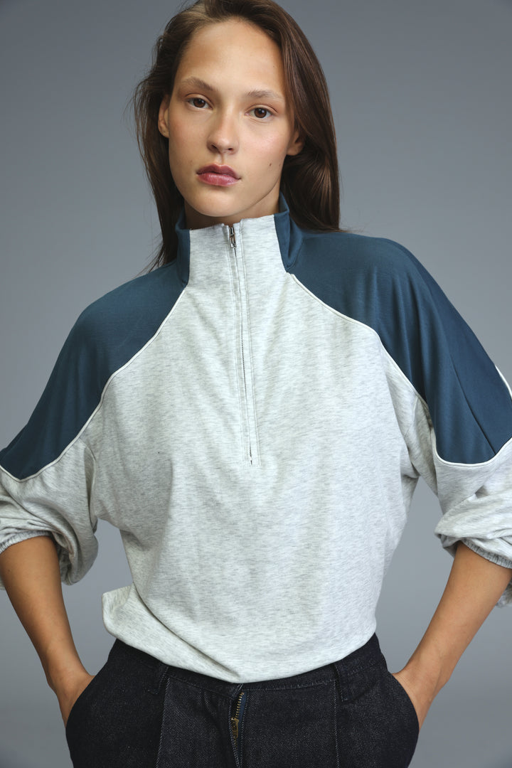 Allure grey sweatshirt with raglan navy blue sleeves and half-zip front in a soft textured fabric visible from the front