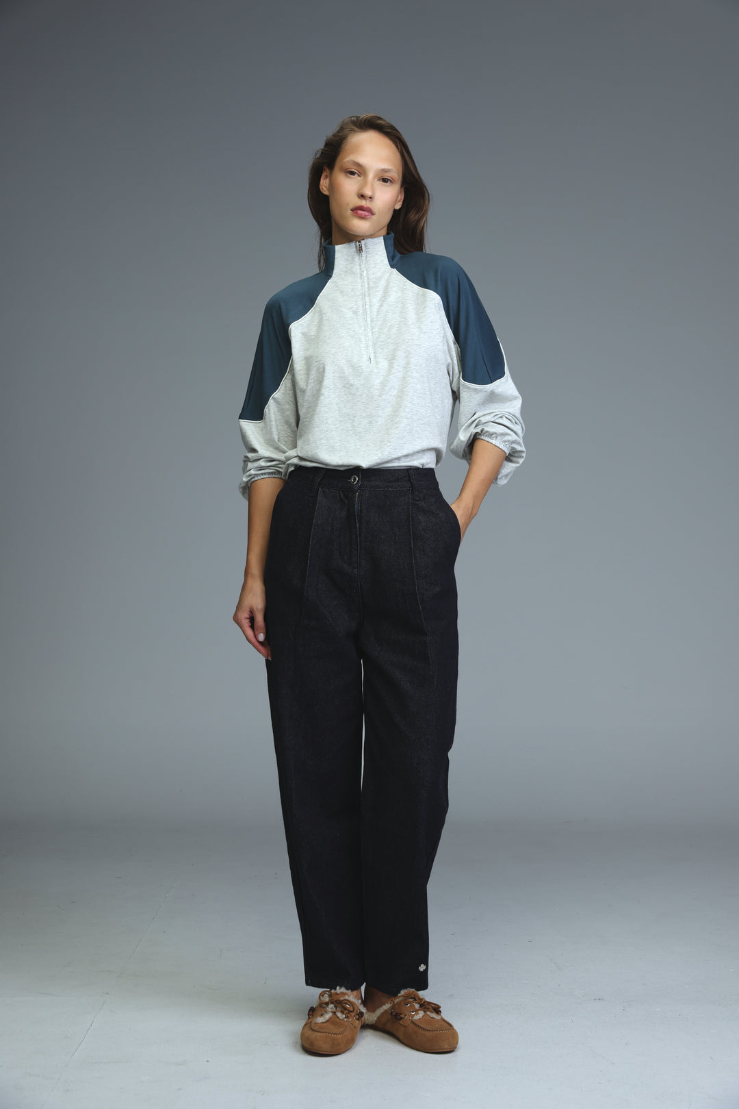 A woman wearing a front view two-tone high-necked athletic top paired with star 250 dark blue tailored denim jeans