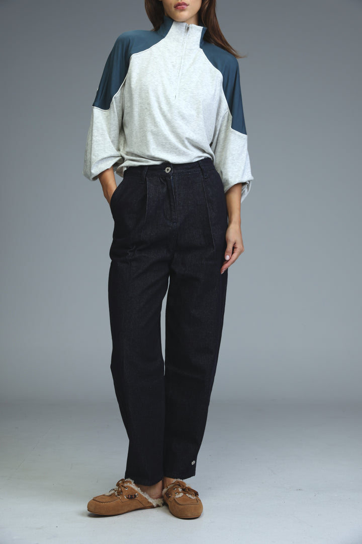 A woman wearing a dark blue tailored denim with a two-tone quarter-zip top featuring navy and light gray panels