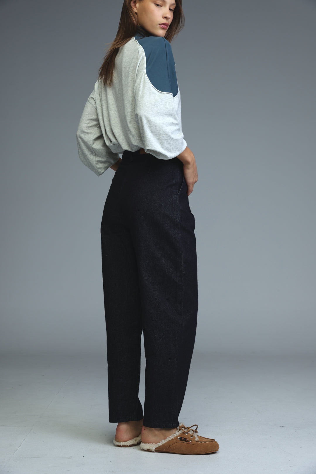 A model wears dark blue tailored denim high-waisted wide-leg trousers with a relaxed straight-cut silhouette