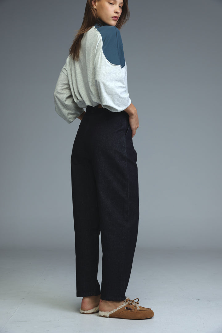 A model wears dark blue tailored denim high-waisted wide-leg trousers with a relaxed straight-cut silhouette
