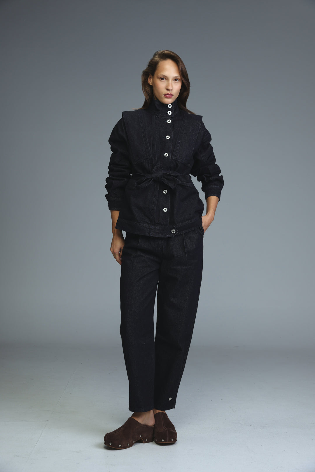 Prestige dark blue denim jacket with high collar and cinched waist paired with matching trousers shown from front view
