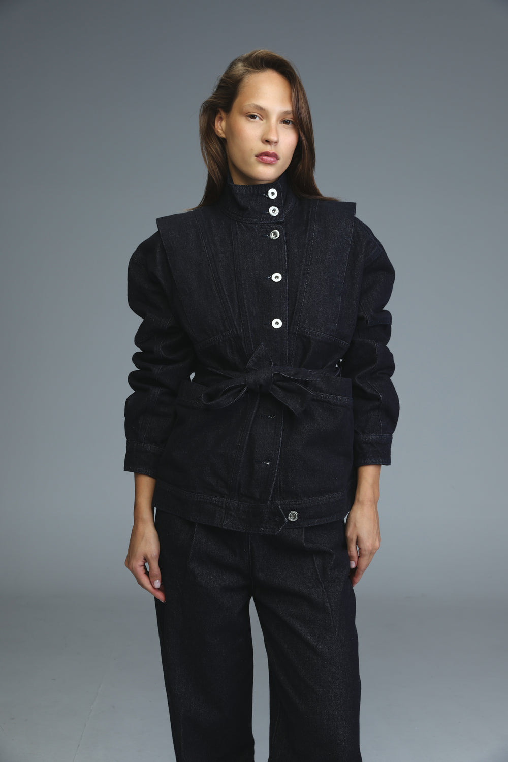 Dark blue denim jacket front view with white buttons and belted waist
