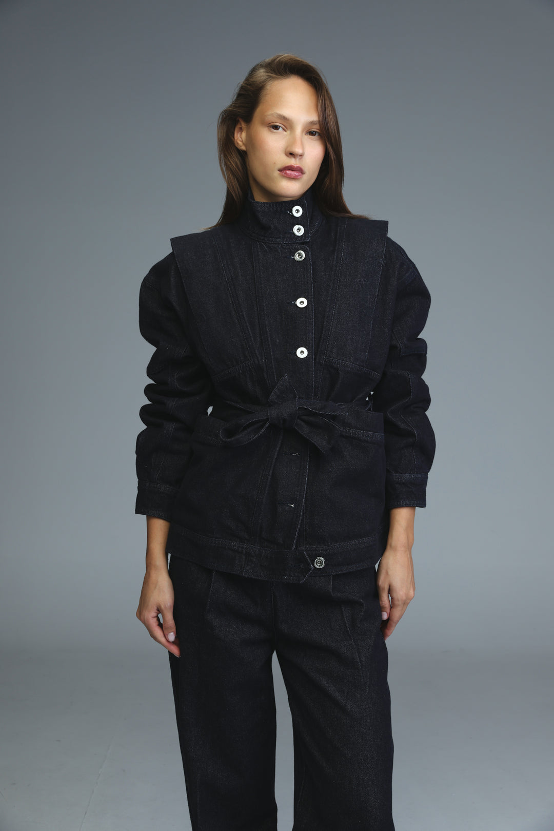 Dark blue denim jacket front view with white buttons and belted waist
