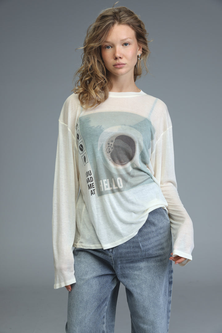 White long-sleeved Hello Coffee Cream shirt with a faded blue and gray eye design and text you mad me at hello on front
