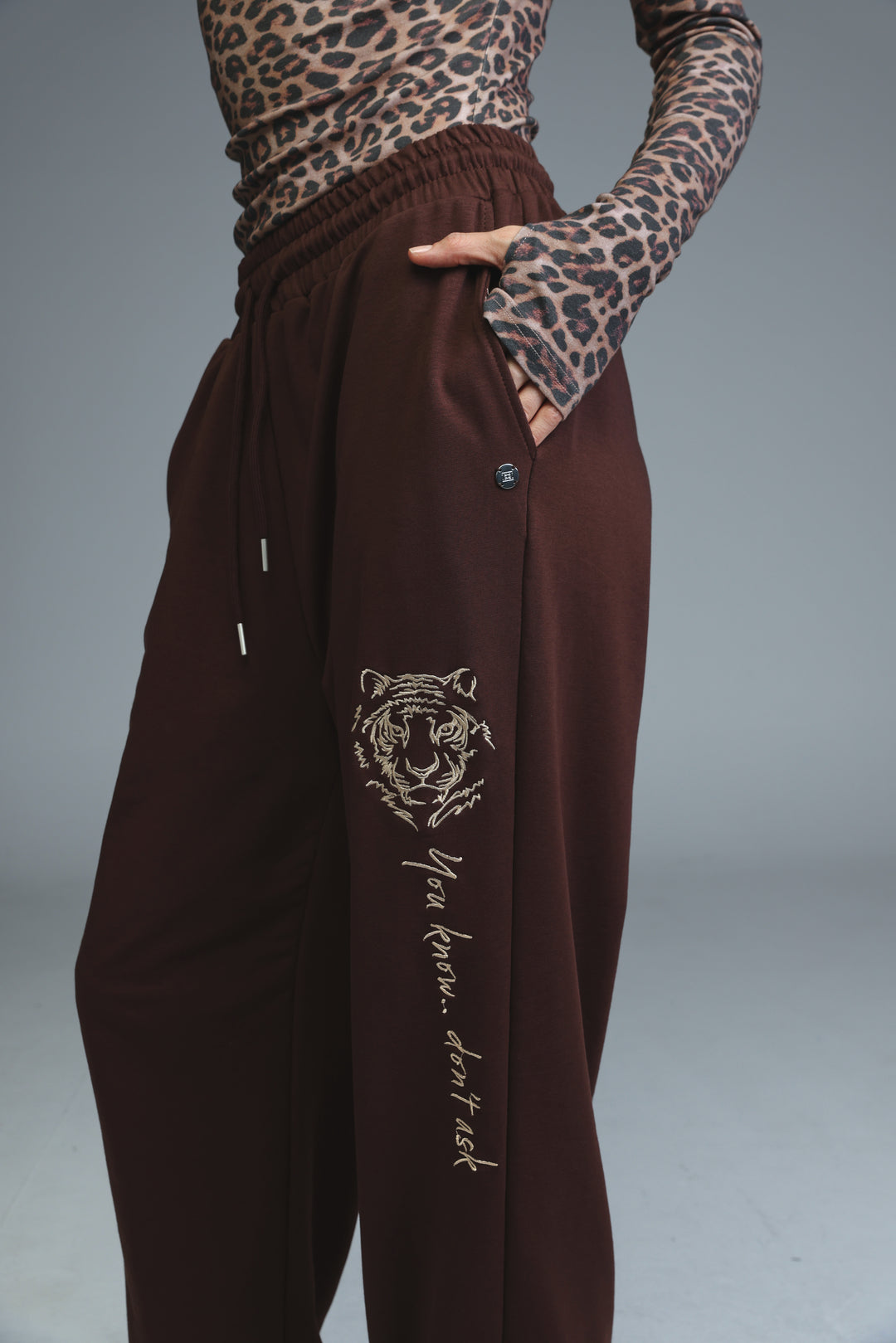 Brown tiger-themed joggers with embroidered design and side pocket shown from the front