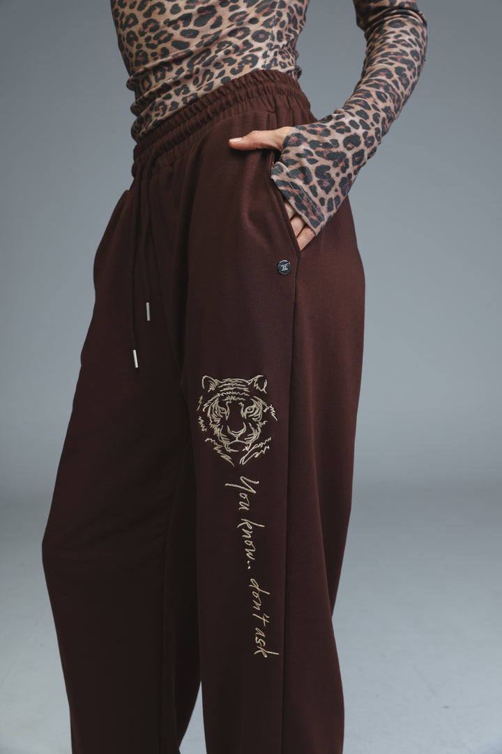 Brown tiger-themed joggers with embroidered design and side pocket shown from the front