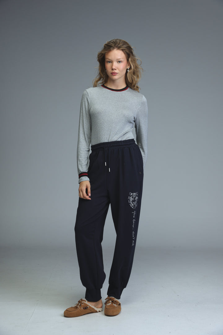 Navy blue jogger pants with white tiger embroidery and cursive text along the leg shown from the side view