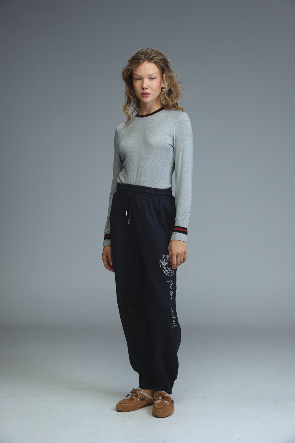 Navy blue sweatpants with white embroidered rose and cursive text on leg, elastic cuffs, and waist drawstrings