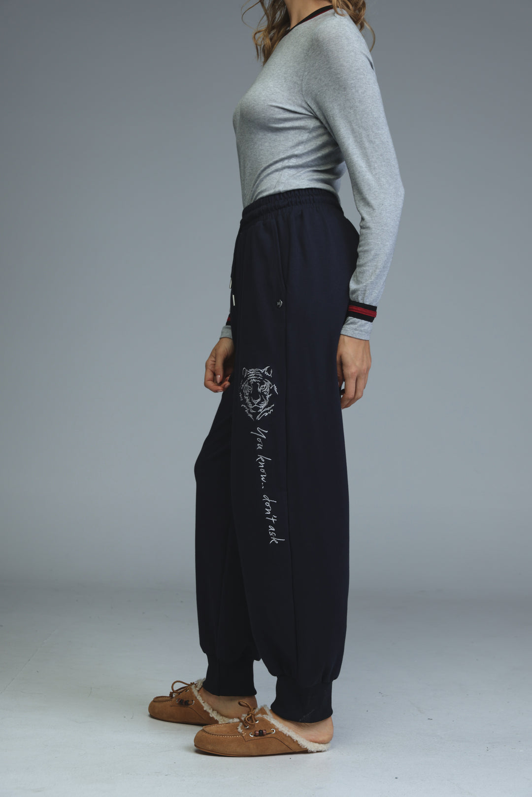 Navy blue joggers with white tiger embroidery and vertical you know dont ask stitching along the leg front view