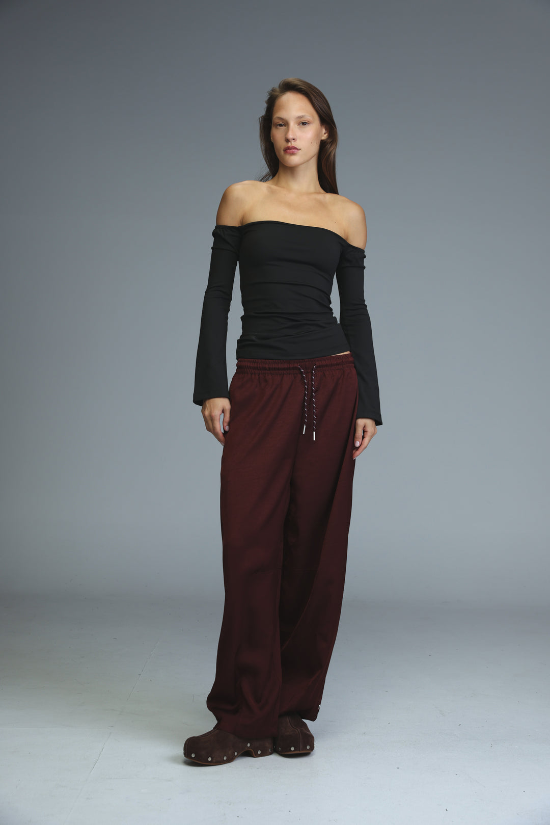 Golden wine wide-leg bottoms with drawstring waistband and metallic eyelets paired with black off-shoulder top front view
