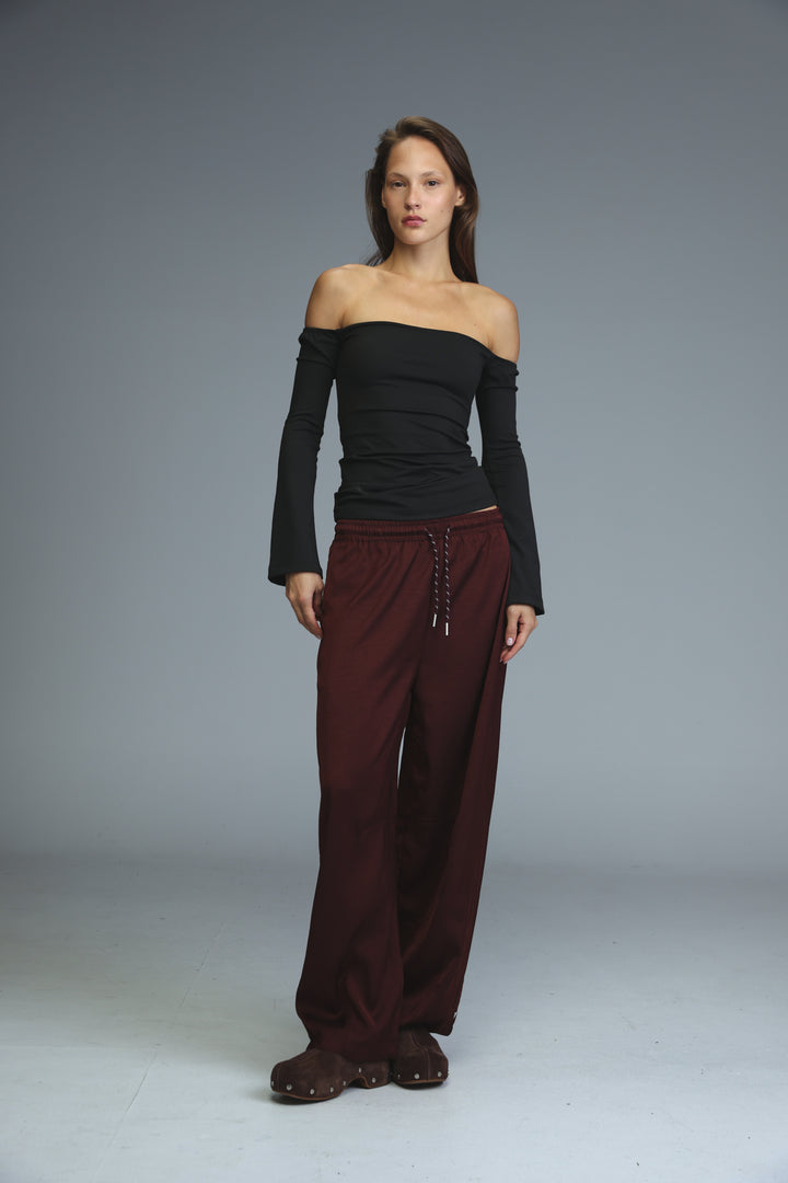 The front view of wide-leg golden wine bottoms with a drawstring waistband paired with a black off-the-shoulder top