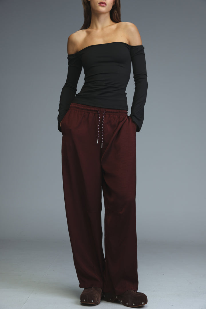 The model wears golden wine wide-leg trousers with an elastic waistband and drawstring closure shown from the front