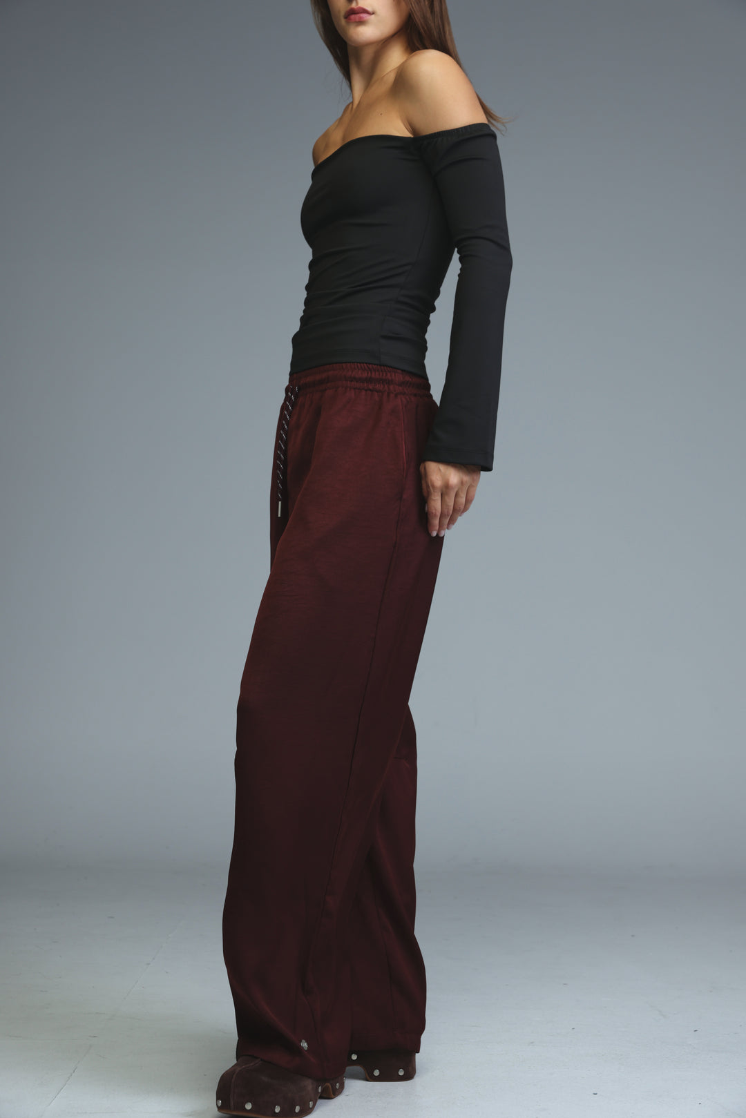 A pair of burgundy wide-leg trousers with a relaxed fit and subtle side detailing shown from the front