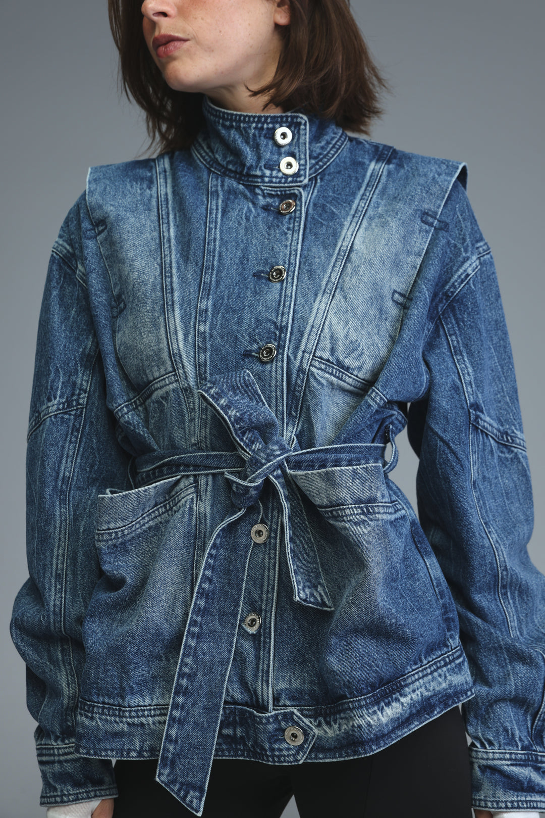 Prestige blue denim jacket with high collar, front button closure, and self-tie belt shown from the front