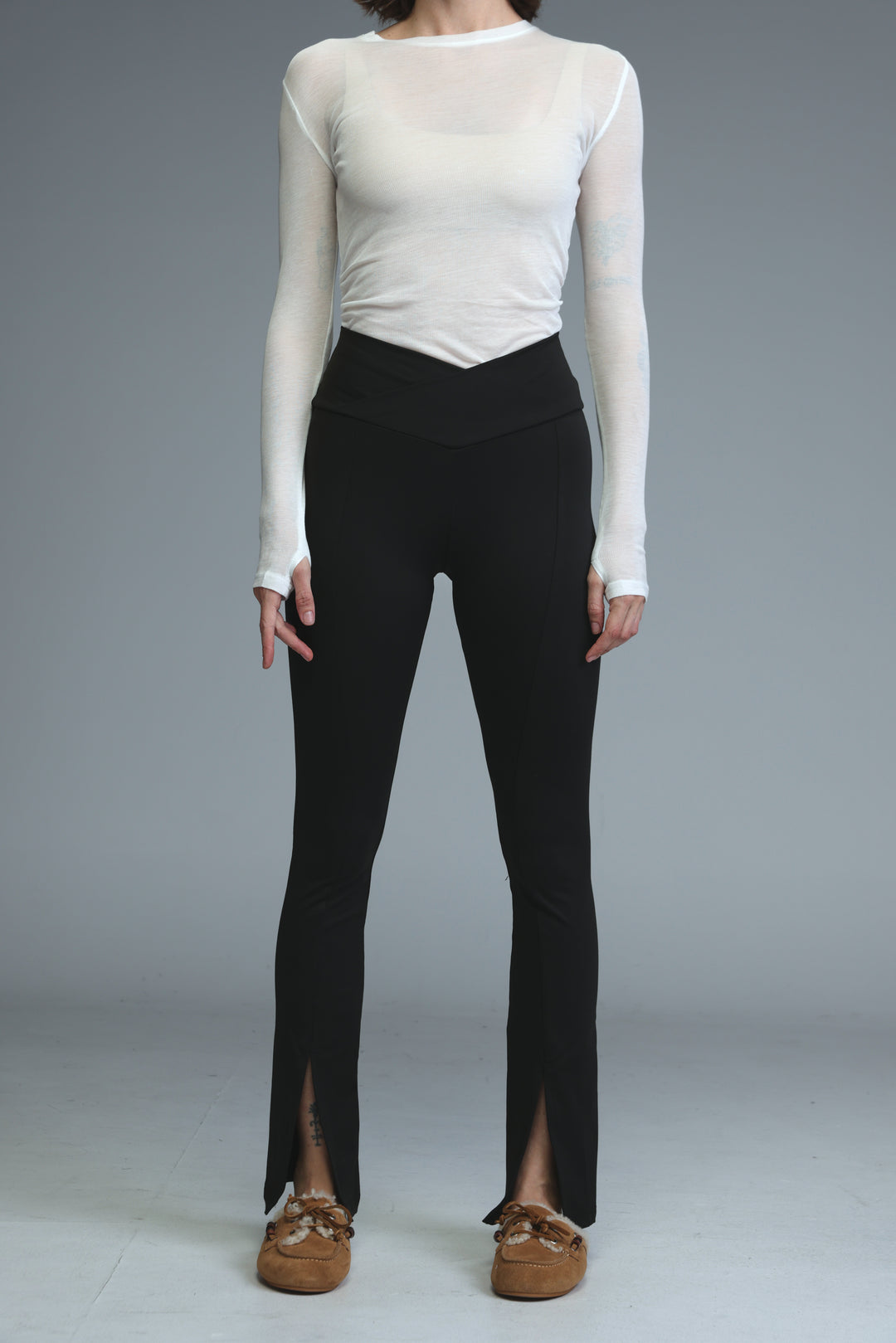 Black high waisted leggings with a front slit detail at the ankle shown from the side view