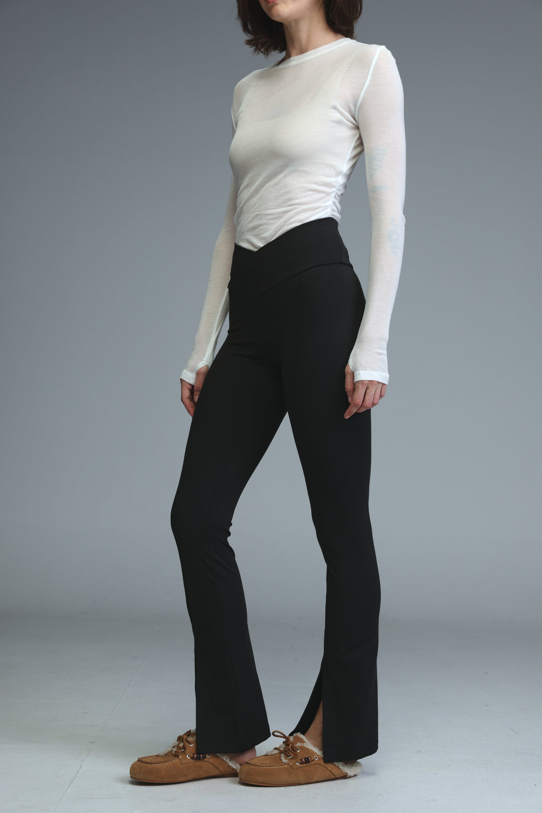 Black high-waisted flared leggings with a front slit at the ankle shown from the side view