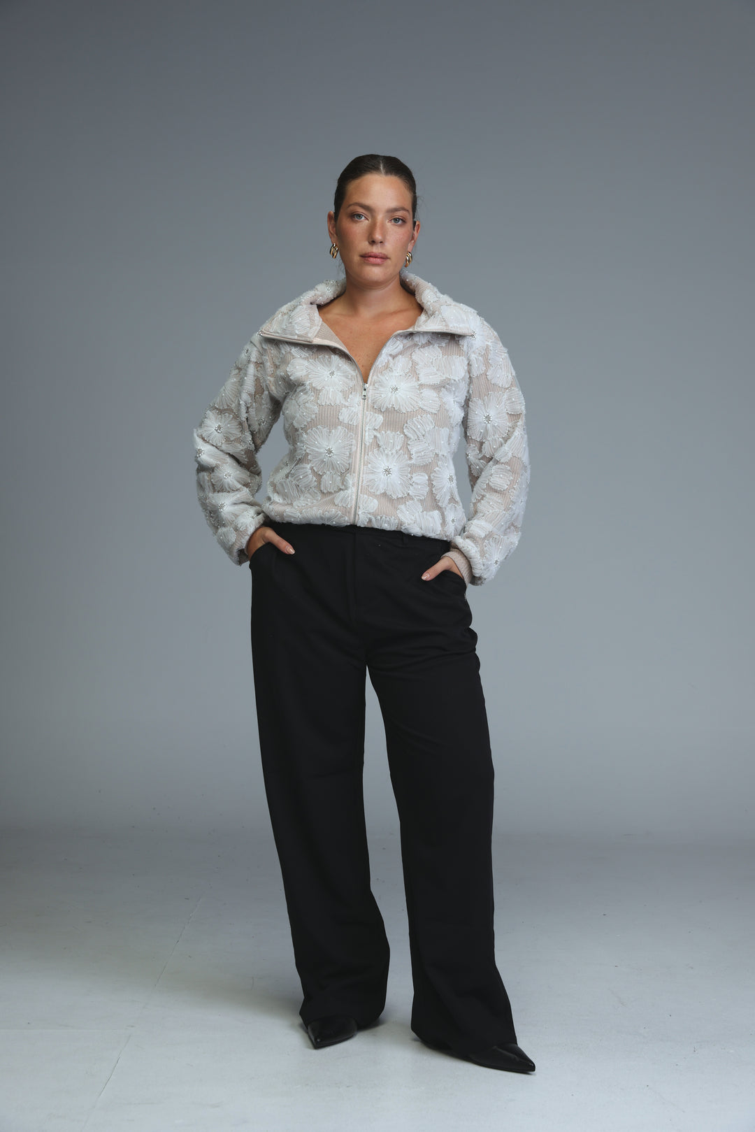 Light gray puffer jacket with plush floral pattern and full-length zipper paired with mid rise tailored black bottoms