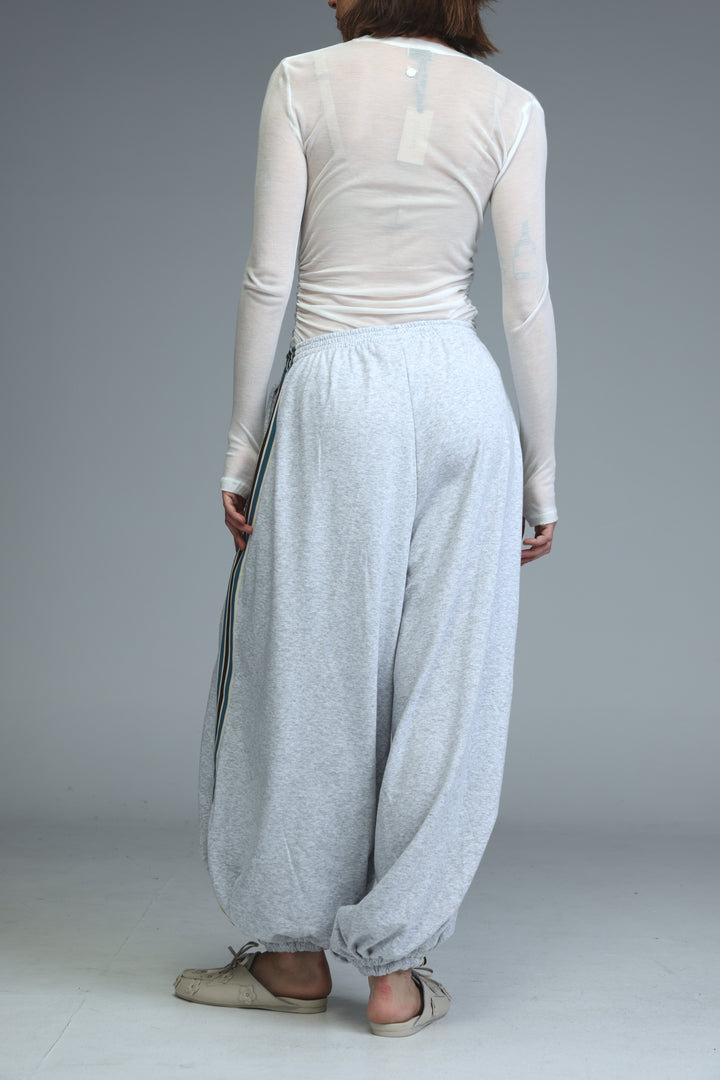 Light gray ballooning joggers with loose fit elastic cuffs and a side stripe detail shown from the front view
