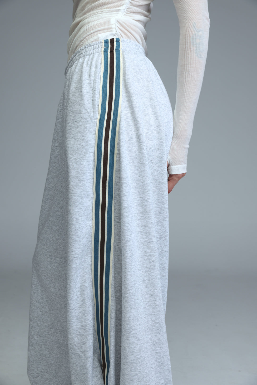 Ballooning grey striped joggers with a vertical teal black and cream stripe down the side seam shown from the side