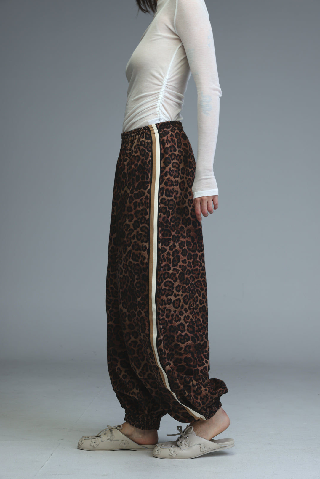 Brown leopard-print harem pants with a cream-colored vertical stripe down the side shown from the front angle