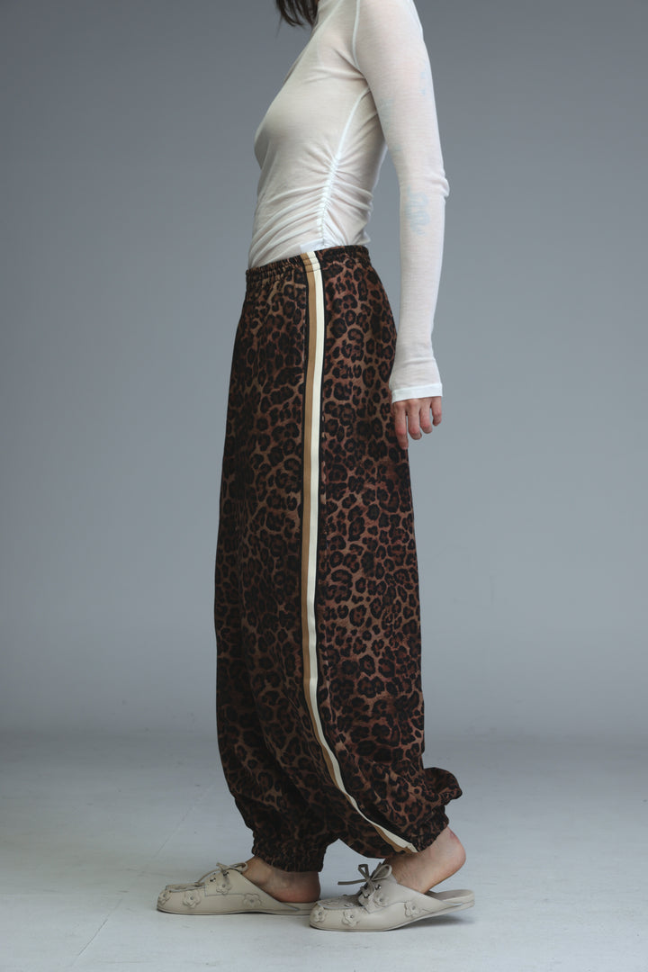 Brown leopard-print harem pants with a cream-colored vertical stripe down the side shown from the front angle