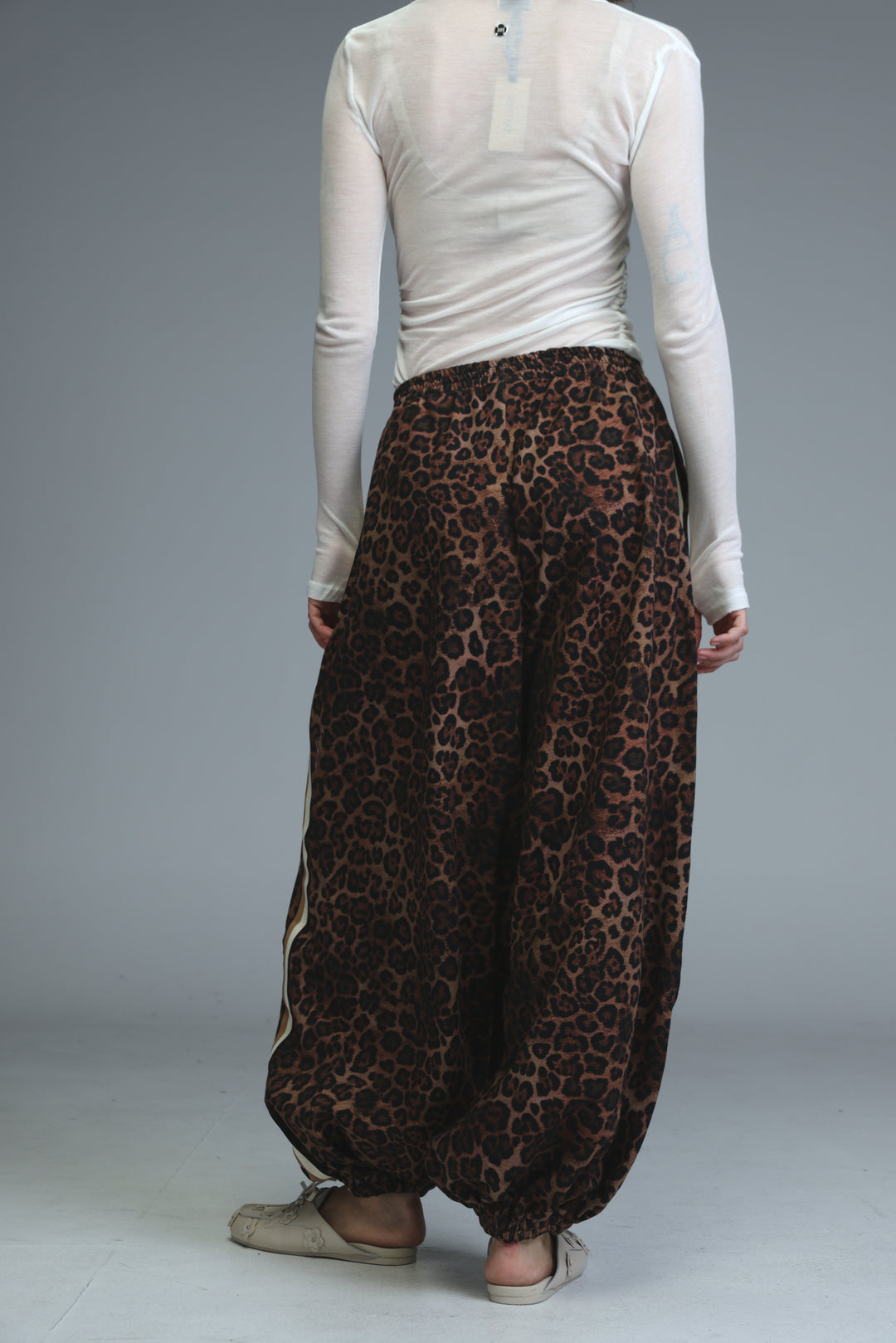 Brown leopard print harem pants with loose flowing silhouette and white side stripes shown from front view