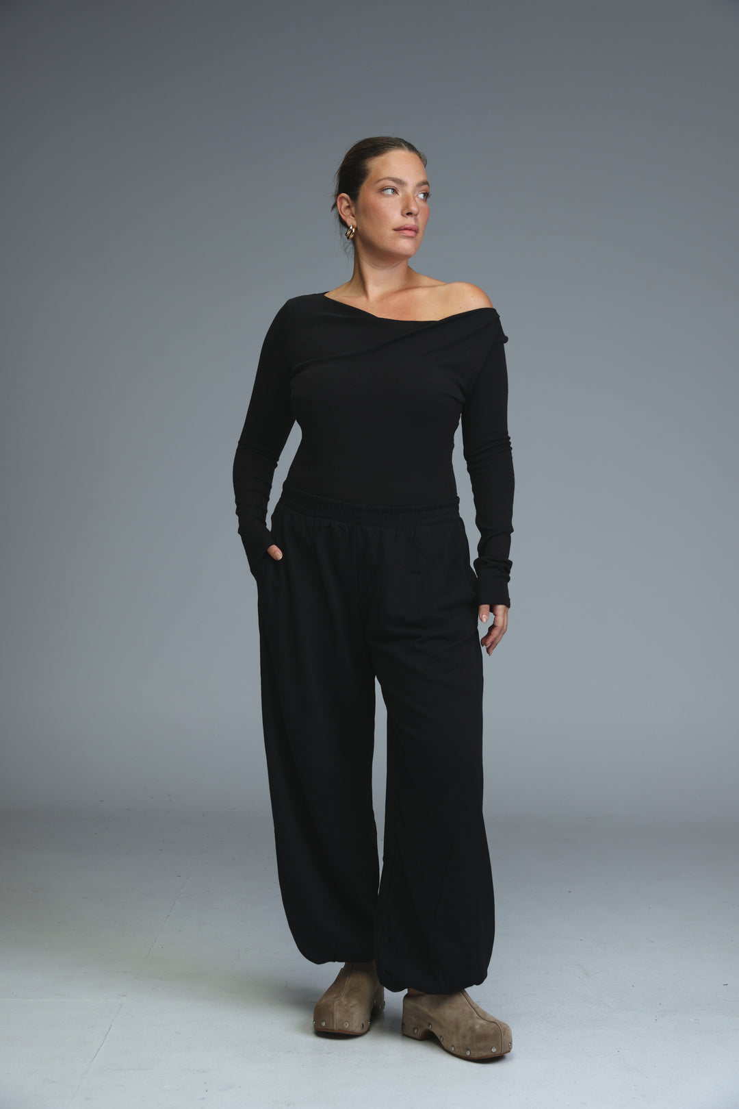 Black off-the-shoulder long-sleeved jumpsuit with wide-leg pants and relaxed fit shown from the front